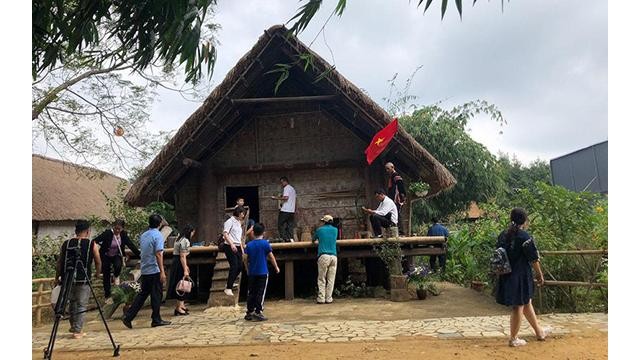 Les touristes visitent la maison Ede au village culturel et touristique ethnique au Vietnam. Photo : NDEL.
