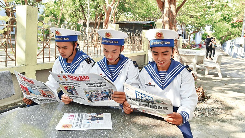 Des soldats dans l'archipel de Truong Sa du Vietnam lisent le Journal Nhân Dân. Photo : NDEL.