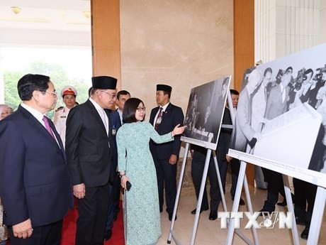 Le Premier ministre Pham Minh Chinh (à gauche) et son homologue malaisien, Anwar Ibrahim, visitent une exposition de photo de l'Agence vietnamienne d'Information. Photo : VNA.