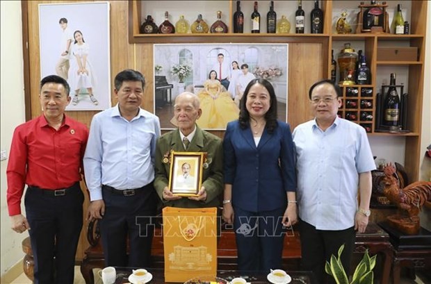 La présidente par intérim Vo Thi Anh Xuan offre un cadeau au vétéran Nguyen Viet Diem. Photo : VNA