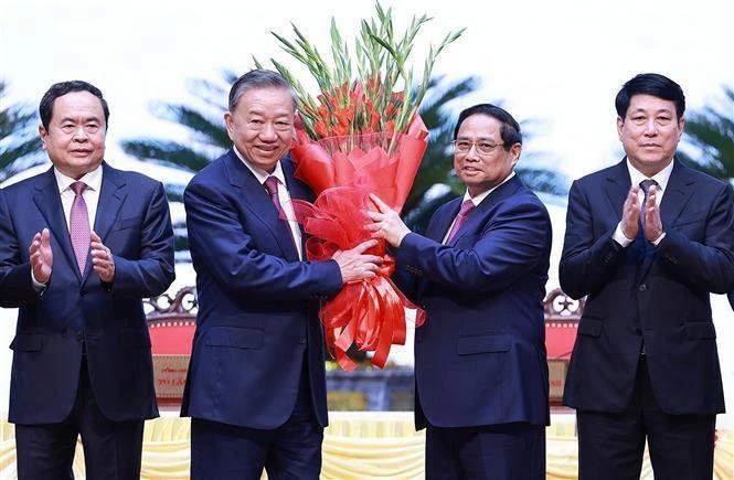 Le Premier ministre Pham Minh Chinh (2e à partir de la droite) offre des fleurs à Tô Lâm (2e à partir de la gauche) après son élection au poste de secrétaire général du Comité central du Parti du XIIIe mandat. Photo : VNA.