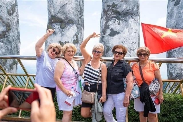 Des touristes étrangers posent pour une photo sur le célèbre Golden Bridge à l'intérieur du complexe Ba Na Hills Sun World dans la ville de Da Nang. Photo : VNA.