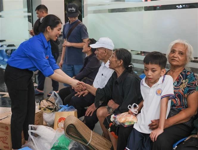 Des jeunes bénévoles aident les habitants du quartier de Yen Phu, à Hanoi, à se rendre dans un endroit plus sûr. Photo : VNA.