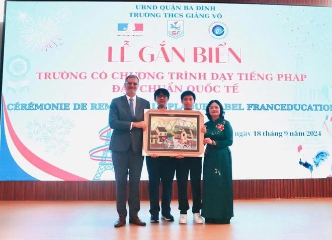 La directrice du collège Giang Vo, Tô Thi Hai Yên, et ses élèves remettent un cadeau à l'ambassadeur de France au Vietnam, Olivier Brochet. Photo : CTV/CVN.