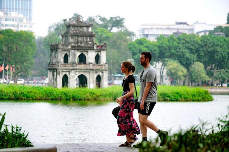 Des touristes étrangers se promènent au bord du lac Hoàn Kiêm. Photo : tuoitre.vn