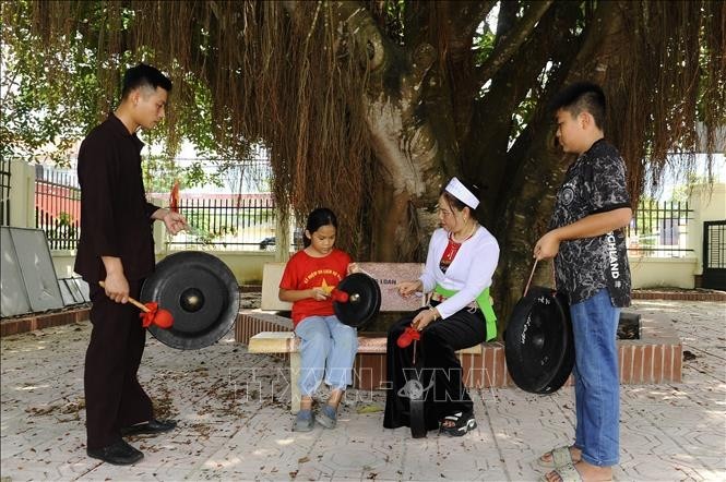 Des jeunes Mường apprennent à jouer le gong. Photo : VNA.