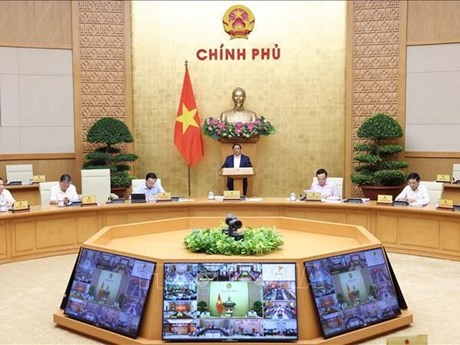 Le PM Pham Minh Chinh (debout) préside la réunion périodique de mars entre le gouvernement et les localités. Photo : VNA.
