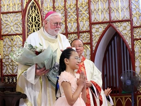 Une jeune fille présente des fleurs à l’archevêque Paul Richard Gallagher, secrétaire du Vatican pour les Relations avec les États et les organisations internationales. Photo : VNA.