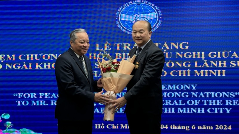 Le président de l’antenne de l'Union des organisations d'amitié du Vietnam à Hô Chi Minh-Ville, Do Viet Ha (à gauche), félicite le consul général de Singapour, Kho Ngee Seng Roy, pour se voir décerner l’insigne « Pour la paix et l’amitié entre les nations ». Photo: VOV. 