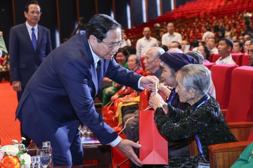 Le Premier ministre Pham Minh Chinh remet des cadeaux à des personnes ayant rendu des services méritoires à la révolution. Photo: VNA.