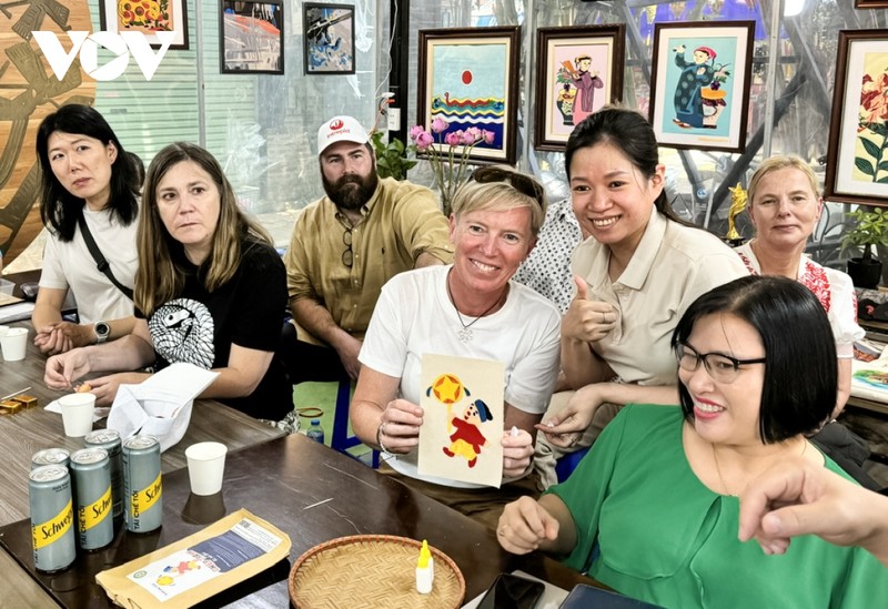 En visitant l'atelier Vun Art, les touristes étrangers peuvent expérimenter la réalisation de peintures sur tissus avec l’aide des artisans handicapés de l’atelier. Photo: VOV.