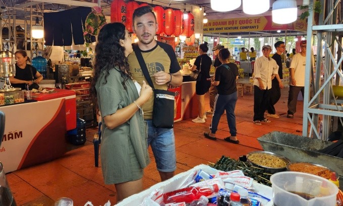 Maria et son petit ami cherchent des plats vietnamiens lors du festival le soir du 23 octobre. Photo : Bich Phuong. 