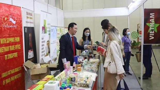 Le représentant du Service commercial du Vietnam à Singapour, Cao Xuân Thang, présente des produits vietnamiens aux visiteurs étrangers. Photo : VNA.