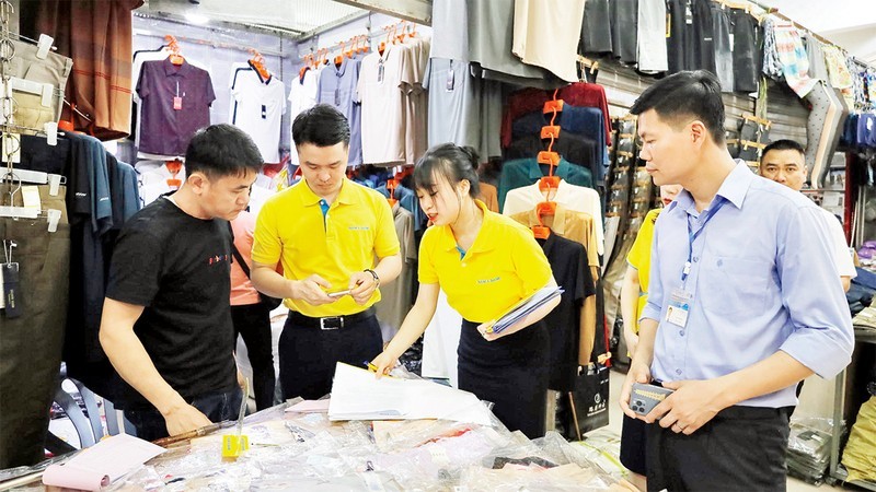 Des employés de banque guident les commerçants au marché de Mong Cai sur les paiements dématérialisés.