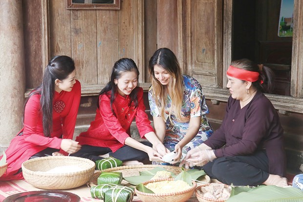 Des touristes étrangères découvrent la préparation de banh chung (gâteau de riz gluant) à Phu Tho. Photo : VNA