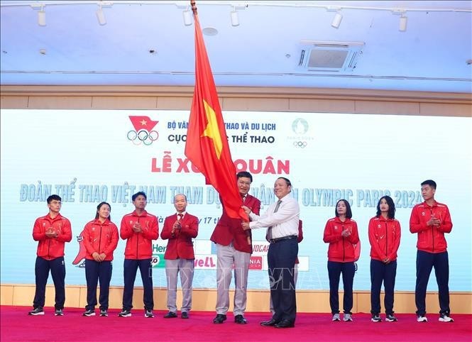 Le ministre de la Culture, des Sports et du Tourisme, Nguyen Van Hung (droite), remet le drapeau symbolisant la détermination à concourir au chef de la délégation vietnamienne aux JO de Paris 2024, Dang Ha Viet. Photo : VNA.