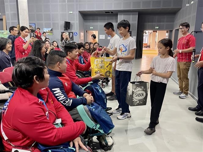 Des Vietnamiens en France offrent des cadeaux aux sportifs handicapés vietnamiens. Photo : VNA.