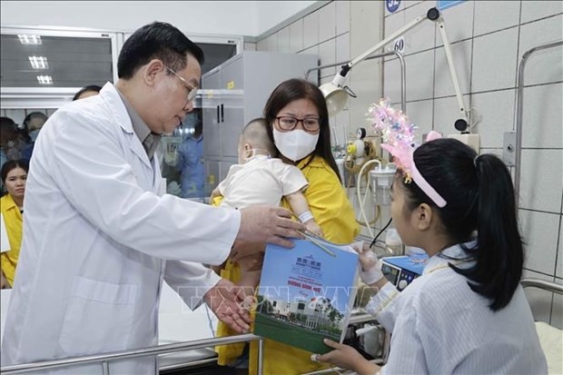 Le président de l'Assemblée nationale, Vuong Dinh Huê, remet un cadeau à une fille soignées à l'hôpital Bach Mai après l'incendie d'un immeuble d'habitation dans l'arrondissement de Thanh Xuan, Hanoï. Photo: VNA