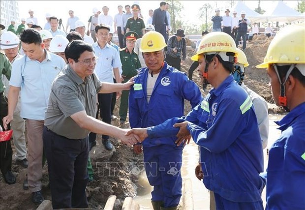 Le Premier ministre Pham Minh Chinh serre la main d'un ouvrier sur le chantier du projet de rocade 3 de Hô Chi Minh-Ville. Photo : VNA.