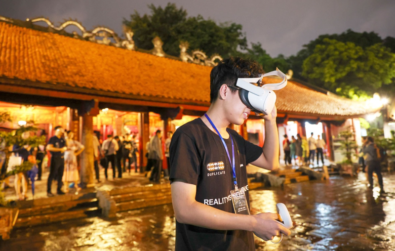 Un touriste découvre la technologie de réalité virtuelle lorsqu'il visite le Temple de la Littérature. Photo: hanoimoi