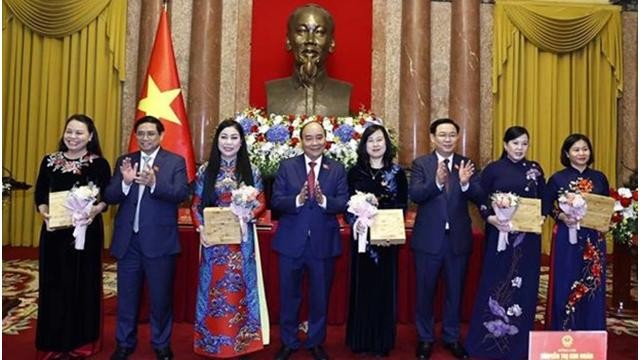 Le Président Nguyen Xuan Phuc (4e, gauche), le Premier ministre Pham Minh Chinh (2e gauche), le Président de l'Assemblée nationale Vuong Dinh Hue (3e, droite) offrent des cadeaux aux déléguées. Photo: VNA