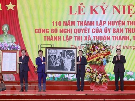 Le Président de l'Assemblée nationale, Vuong Dinh Huê, remet la photo de l'Oncle Hô et la Résolution du Comité permanent de l'AN aux autorités de Thuân Thành sur la création de la cité municipale de Thuân Thành. Photo : VNA.