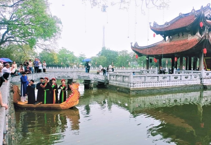 Les membres du Club du chant alterné "Quan họ" du temple Dô se produisent à la maison communale sur un lac du temple Dô. Photo : NDEL.