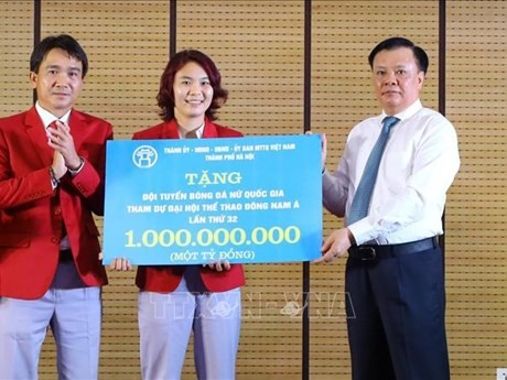 Le secrétaire du Comité du Parti de la ville de Hanoï, Dinh Tien Dung, remet un milliard de dongs de la ville à l'équipe de football féminin du Vietnam qui a remporté la médaille d’or aux SEA Games 32 au Cambodge. Photo : VNA