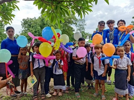 Des jeunes volontaires de Hô Chi Minh-Ville et des enfants lao dans une aire de jeux. Photo: CVN