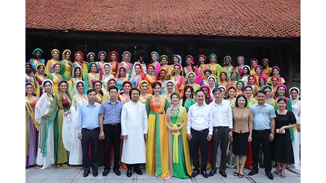 71 belles du concours « Miss Grand International 2023 » et les dirigeants du district de Quôc Oai. Photo: hanoimoi.vn