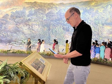 Un touriste étranger scanne le QR code pour se renseigner la peinture panoramique de la campagne de Diên Biên Phu. Photo : http://dic.gov.vn