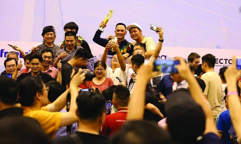 Brandissant le trophée de la Coupe du monde de billard carambole à trois bandes, Trân Duc Minh est entouré de ses fans. Photo : CTV/CVN.