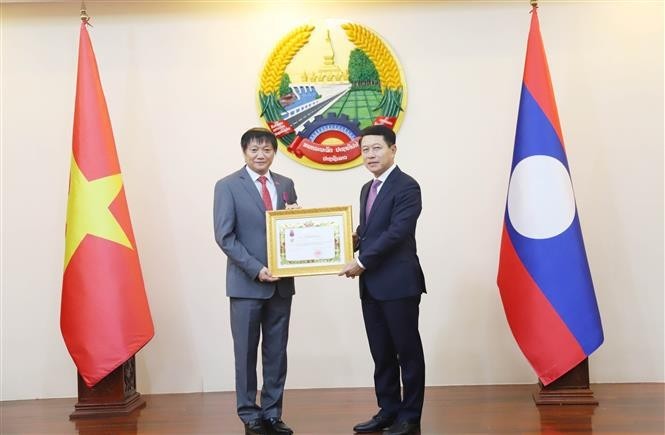 Le vice-Premier ministre et ministre des Affaires étrangères du Laos, Saleumxay Kommasith (droite), remet la noble distinction à l'ambassadeur Nguyen Ba Hung. Photo : VNA.