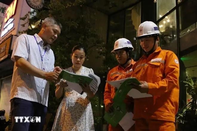 Des représentants de la compagnie d'électricité Gia Dinh demandent aux habitants et aux ménages d'affaires de la rue Dien Bien Phu (arrondissement de Binh Thanh, Hô Chi Minh-Ville) d'éteindre ou de réduire la capacité du système d'éclairage de 50 %. Photo : VNA.