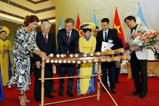 Le président argentin Mauricio Macri joue des instruments de musique traditionnels vietnamiens. Photo : VNA.