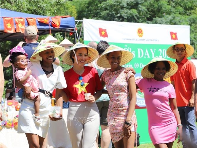 Des amis sud-africains prenant des photos souvenirs avec des chapeaux coniques vietnamiens lors de l'événement. Photo : VNA 