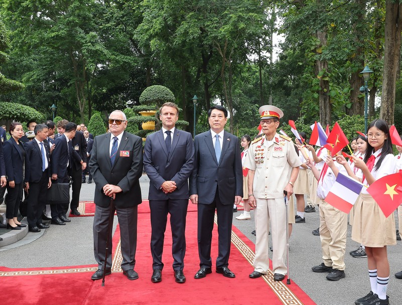 Le président vietnamien Luong Cuong et le président français Emmanuel Macron aux côtés des deux anciens combattants Pham Minh Nghia et William Schilardi. Photo : VNA.