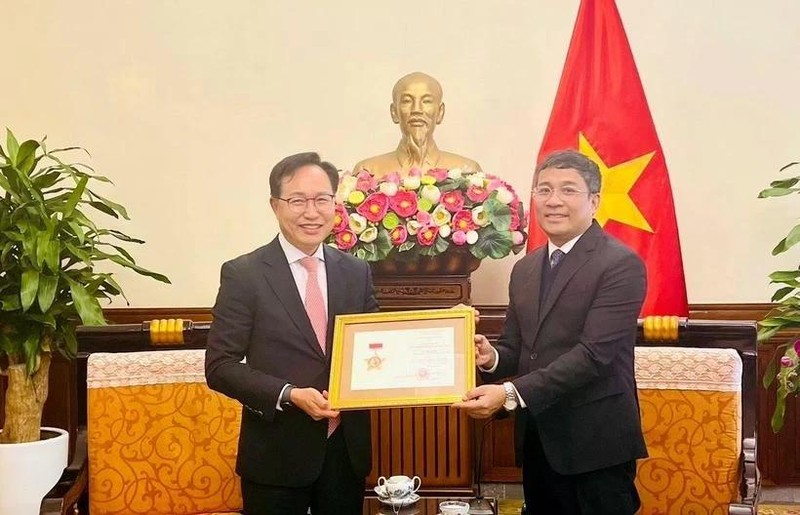 Le vice-ministre permanent des Affaires étrangères Nguyên Minh Vu (à droite) remet l’insigne «Pour la cause des affaires étrangères du Vietnam» au directeur général de Samsung Vietnam, Choi Joo Ho, à Hanoi, le 13 février. Photo : VNA.