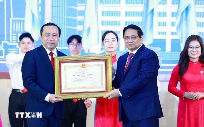 Le Premier ministre Pham Minh Chinh remet l'Ordre du Travail de première classe, décerné par le président de la République, à l'Université nationale de Hô Chi Minh-Ville. Photo : VNA.