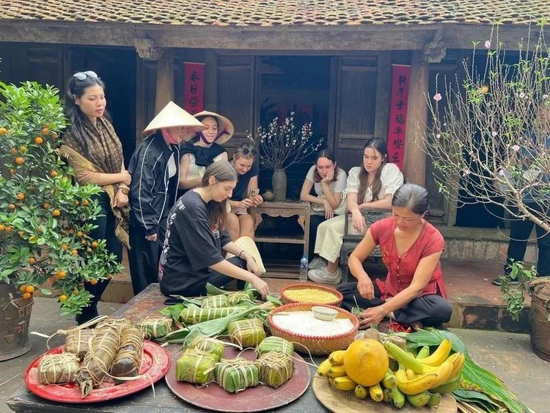 Des touristes étrangers essaient de confectionner des "banh chung" à l'ancien village de Duong Lam. Photo : VNA. 