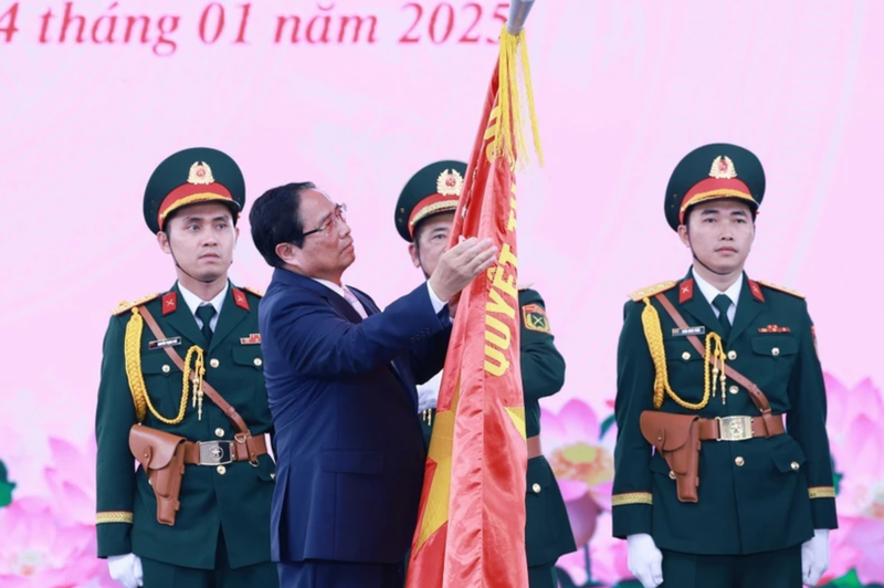 Le Premier ministre Pham Minh Chinh épingle l'insigne "Héros des forces armées populaires" sur le drapeau traditionnel des forces armées de Hô Chi Minh-Ville. Photo : VNA.