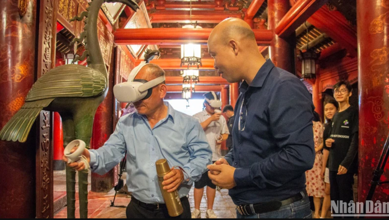 Les touristes découvrent l'écriture calligraphique grâce à la technologie de réalité virtuelle au Temple de la Littérature. Photo : NDEL