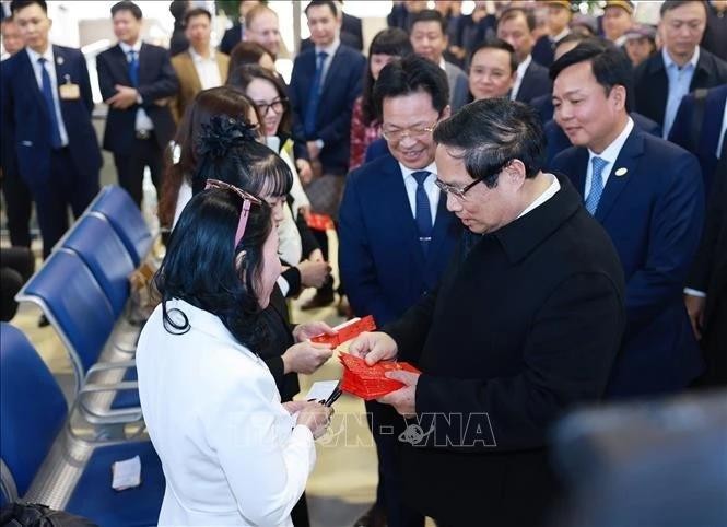 Le Premier ministre Pham Minh Chinh remet des enveloppes rouges symboliques du Têt aux voyageurs et au personnel ferroviaire, à la Gare de Hanoi, le lundi 27 janvier. Photo : VNA