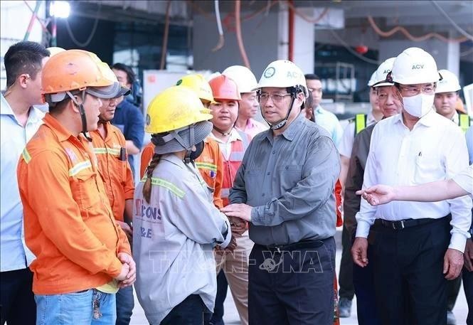 Le Premier ministre Pham Minh Chinh (deuxième à partir de la droite) adresse ses vœux de Nouvel An aux ouvriers du chantier de construction du Terminal 3 de l'aéroport international Tan Son Nhat à Ho Chi Minh-Ville. Photo : VNA.