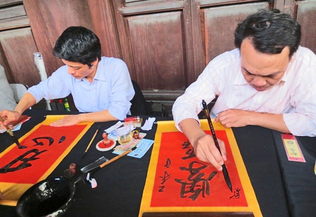 Les lettrés calligraphes écrivent les idéogrammes chinois sur les papiers pourpres avec la plume et l'encre de Chine. Photo: Minh Hanh/NDEL.