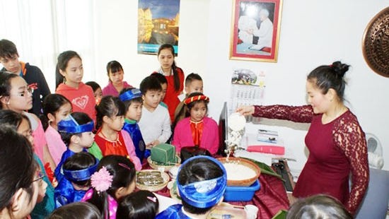 L’enseignante apprend aux enfants à emballer le «banh chung». Photo: NDEL.