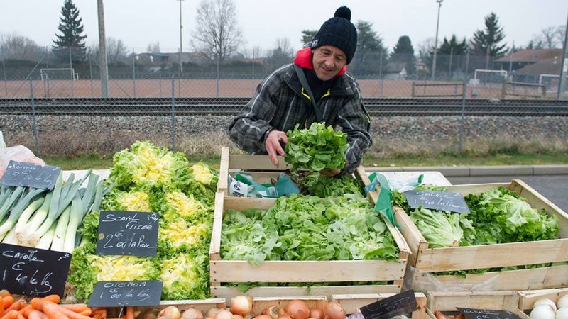 Dans un marché en plein air en Haute-Savoie, en France, un homme vend des légumes produits en respectant les normes recommandées par l’OMS. Photo OMS.