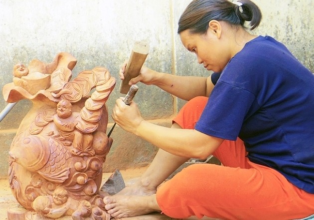 Les sculpteurs de Du Du travaillent avec dextérité, et passion dans la transformation des blocs de bois en œuvres d’art. Photo: Nhât Quang.