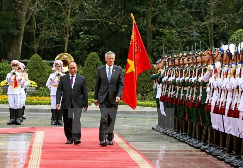 Le PM vietnamien Nguyên Xuân Phuc (à gauche) et son homologue singapourien Lee Hsien Loong inspectent la garde d’honneur lors de la cérémonie de bienvenue à Hanoi. Photo: VNA.