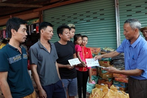 Vo Van Mung, président de l'Association des Vietnamiens dans la province d'Attapeu, offre des cadeaux à trois familles touchées par l'incident. Photo: VNA